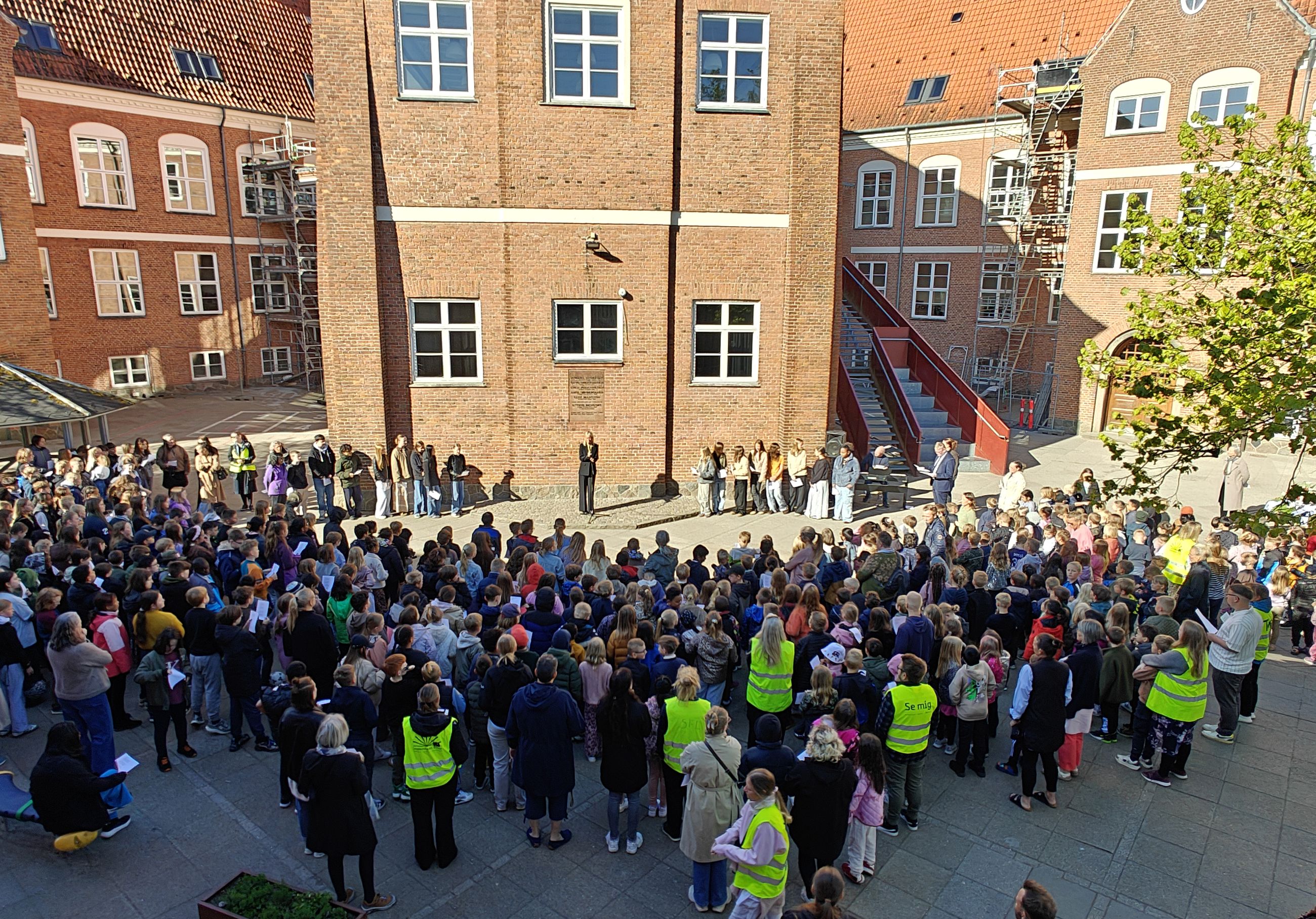 Børnene er samlet foran mindepladen på Hobrovejens Skole