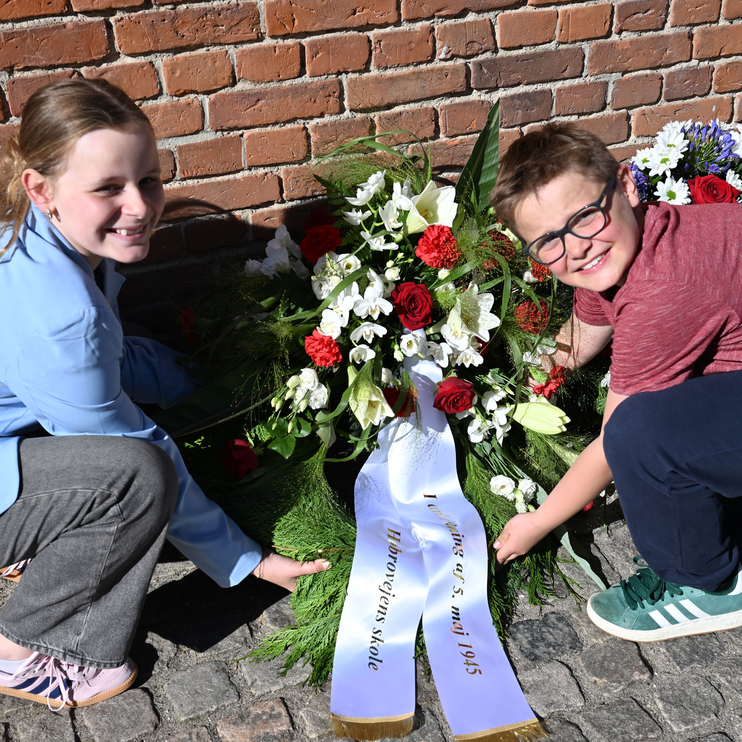 Jasmin Nielsen og Lucas Nielsen fra 3.A lægger kransen ved mindepladen på Hobrovejens Skole