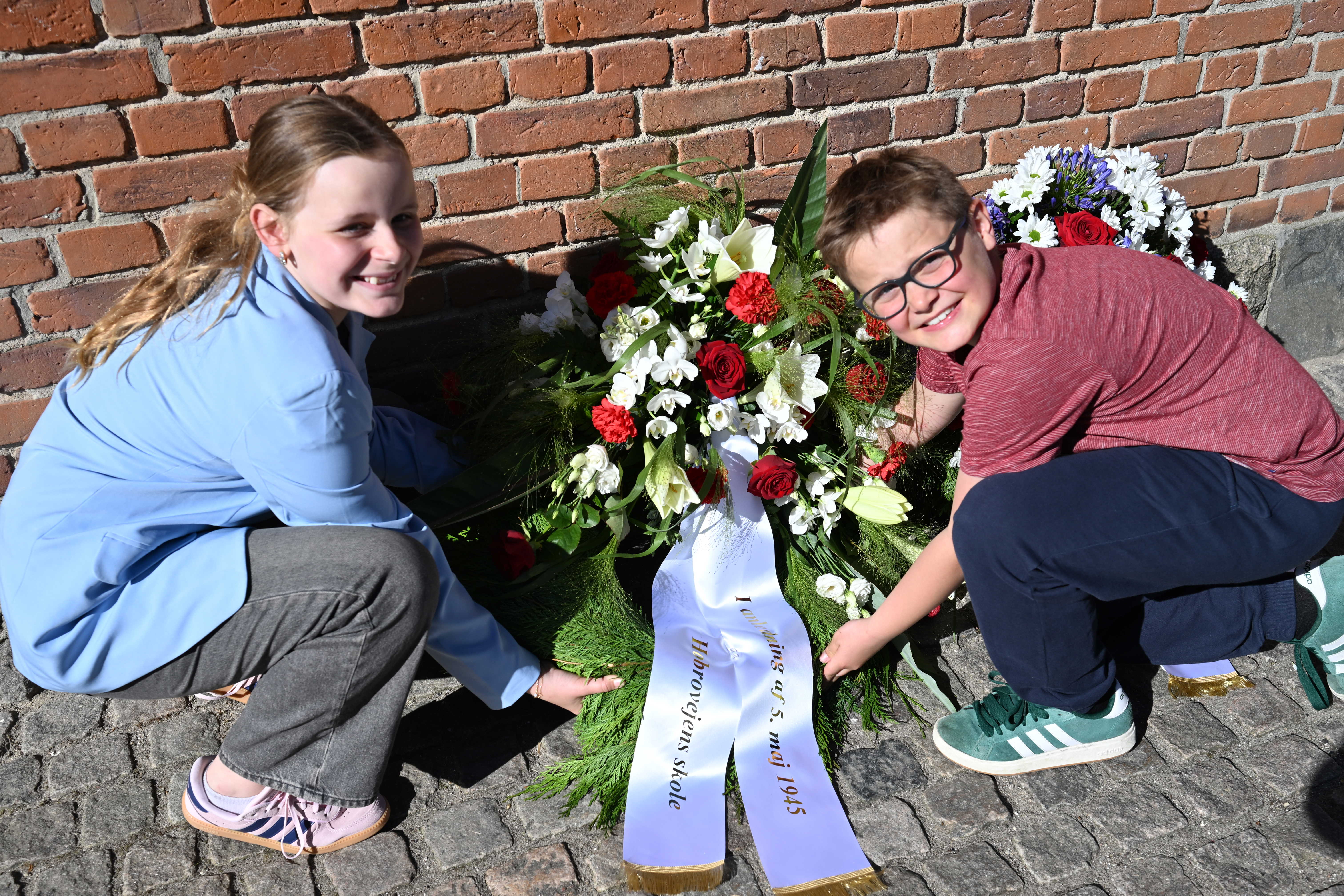 Jasmin Nielsen og Lucas Nielsen fra 3.A lægger kransen ved mindepladen på Hobrovejens Skole